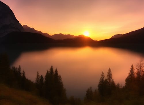 Lake Surrounded with Trees and Mountain during Sunset
