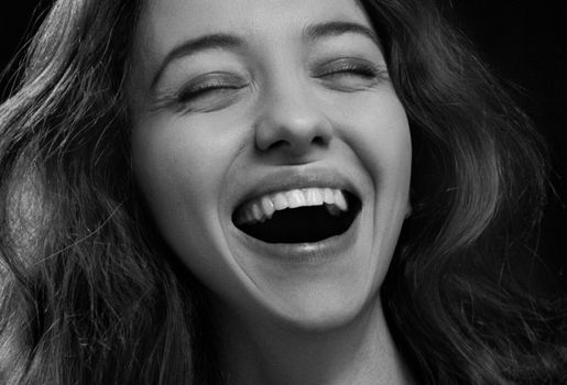 Close-up portrait of a laughing woman, capturing pure happiness in monochrome.
