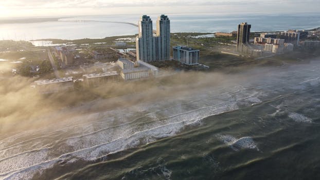 Dramatic aerial view of South Padre Island's foggy coastline with modern architecture and expansive seascape.
