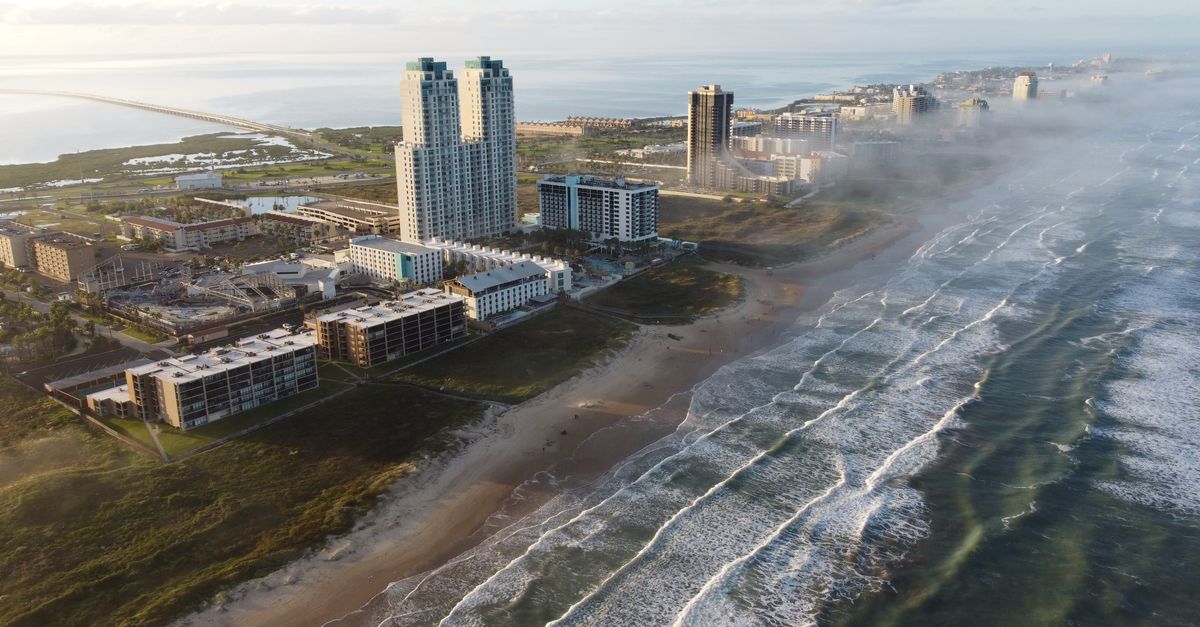 Sunrise aerial of South Padre Island's coastline with tall buildings and waves.