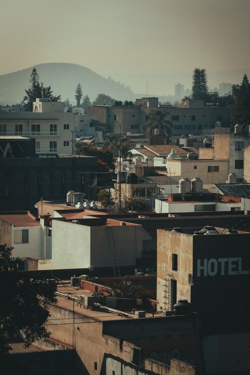 Free Aerial cityscape showcasing rooftops and buildings under a warm sunset sky. Stock Photo