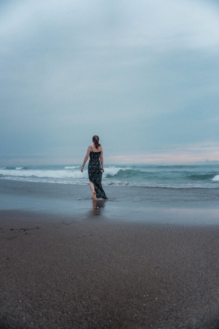 A Person In A Dress Walking At A Beach