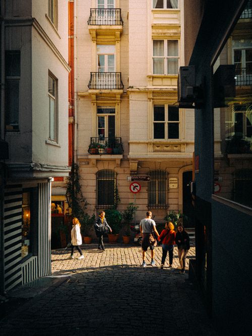 Free People walking on a sunlit cobblestone street in Istanbul, showcasing vibrant urban architecture. Stock Photo
