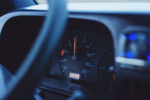 Focused image of a car's speedometer and tachometer under dim lighting, showing mileage and speed.
