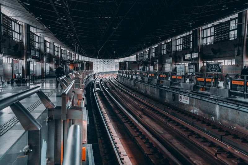 Modern railway station interior showing tracks and platforms in an urban setting.