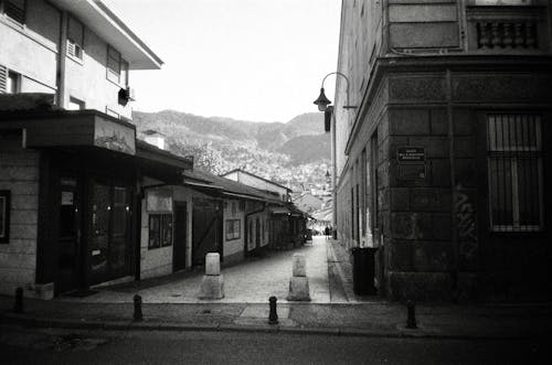 A Grayscale Photo of an Empty Street Between Buildings