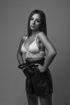 Elegant black and white portrait of a woman in lingerie posing confidently in a studio setting.