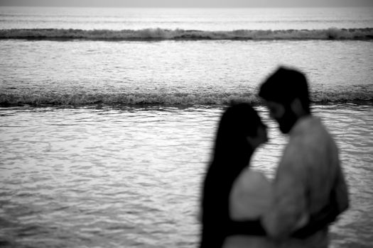 A silhouette of a couple embracing by the sea on Surat beach, India.