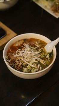 A tantalizing bowl of Asian noodle soup with fresh vegetables and bean sprouts, ready to eat.