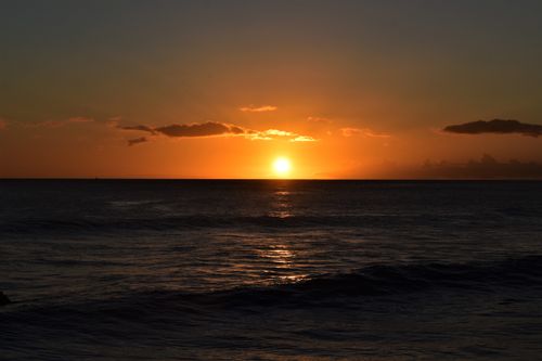Free Stunning sunset over a calm ocean, casting warm golden hues across the horizon. Stock Photo