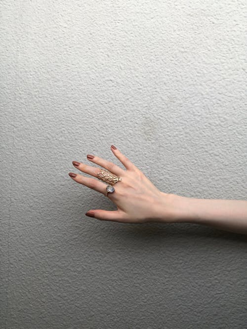 Kostnadsfri bild av betongvägg, bruna naglar, fingrar