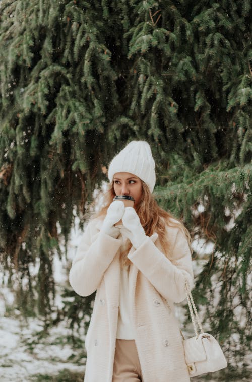 Blonde Woman in Coat under Tree in Winter