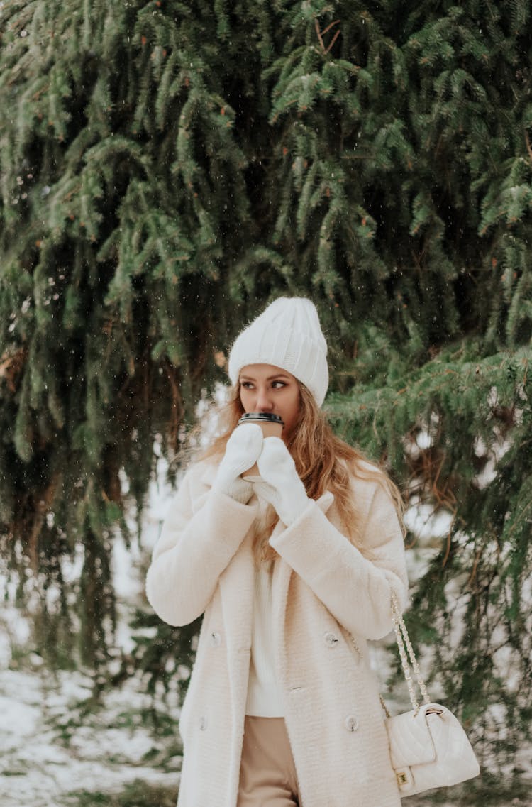 Blonde Woman In Coat Under Tree In Winter