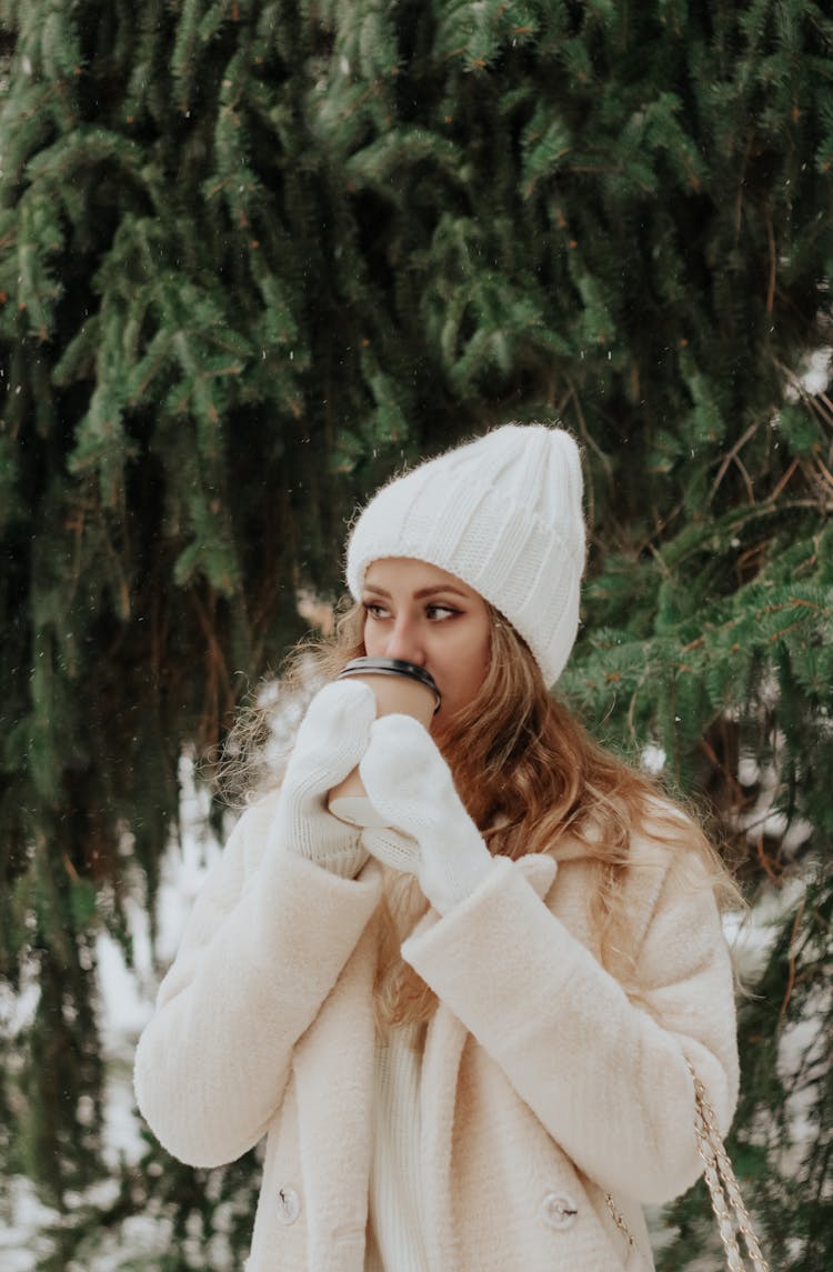 Blonde Woman In Coat And Evergreen Tree Behind