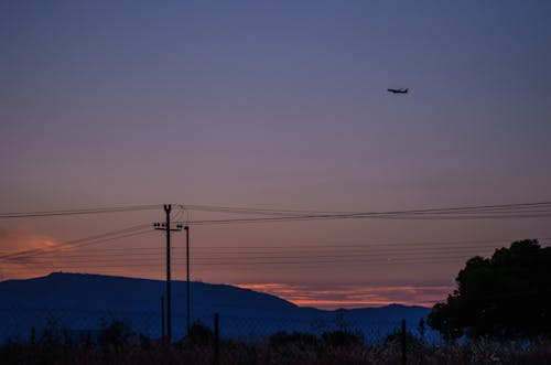 Mountains, High Voltage Lines and a Plane on an Evening Sky