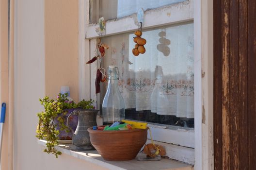 A charming windowsill with a collection of pottery, dried herbs, and plants. Perfect for rustic decor inspiration.