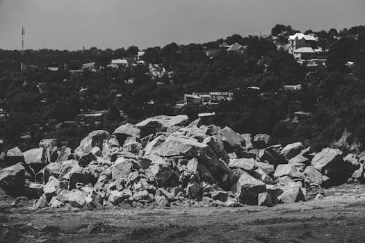 A monochrome image showcasing an urban landscape with a pile of rocks in the foreground.