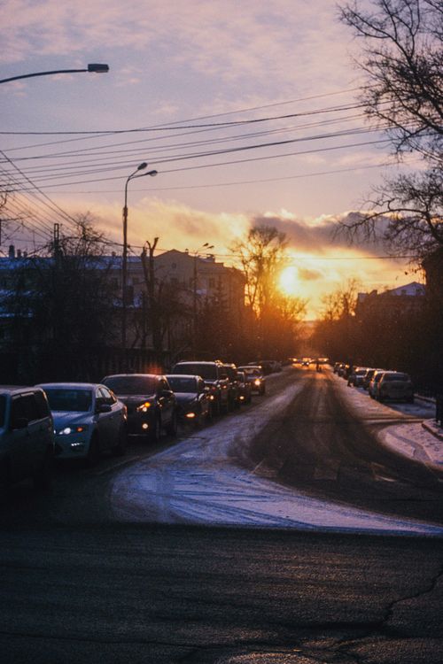 Free A line of cars stuck in traffic during a vibrant winter sunset on a snowy road. Stock Photo