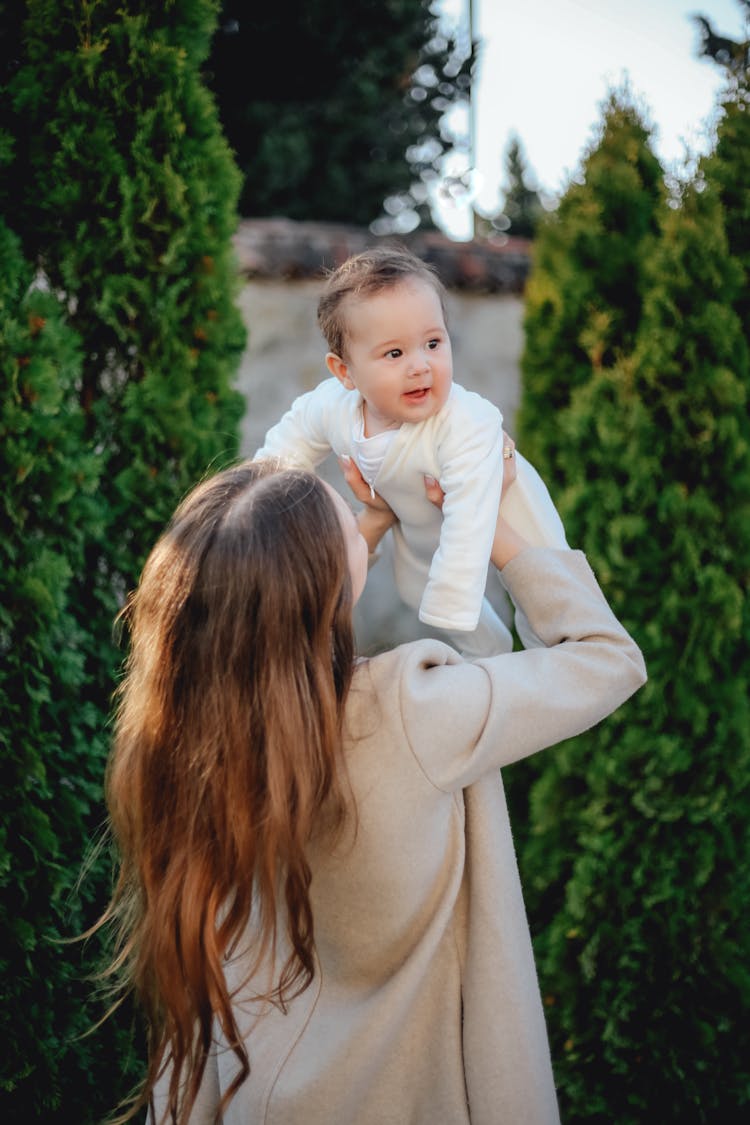 A Woman Lifting Her Baby In The Air 