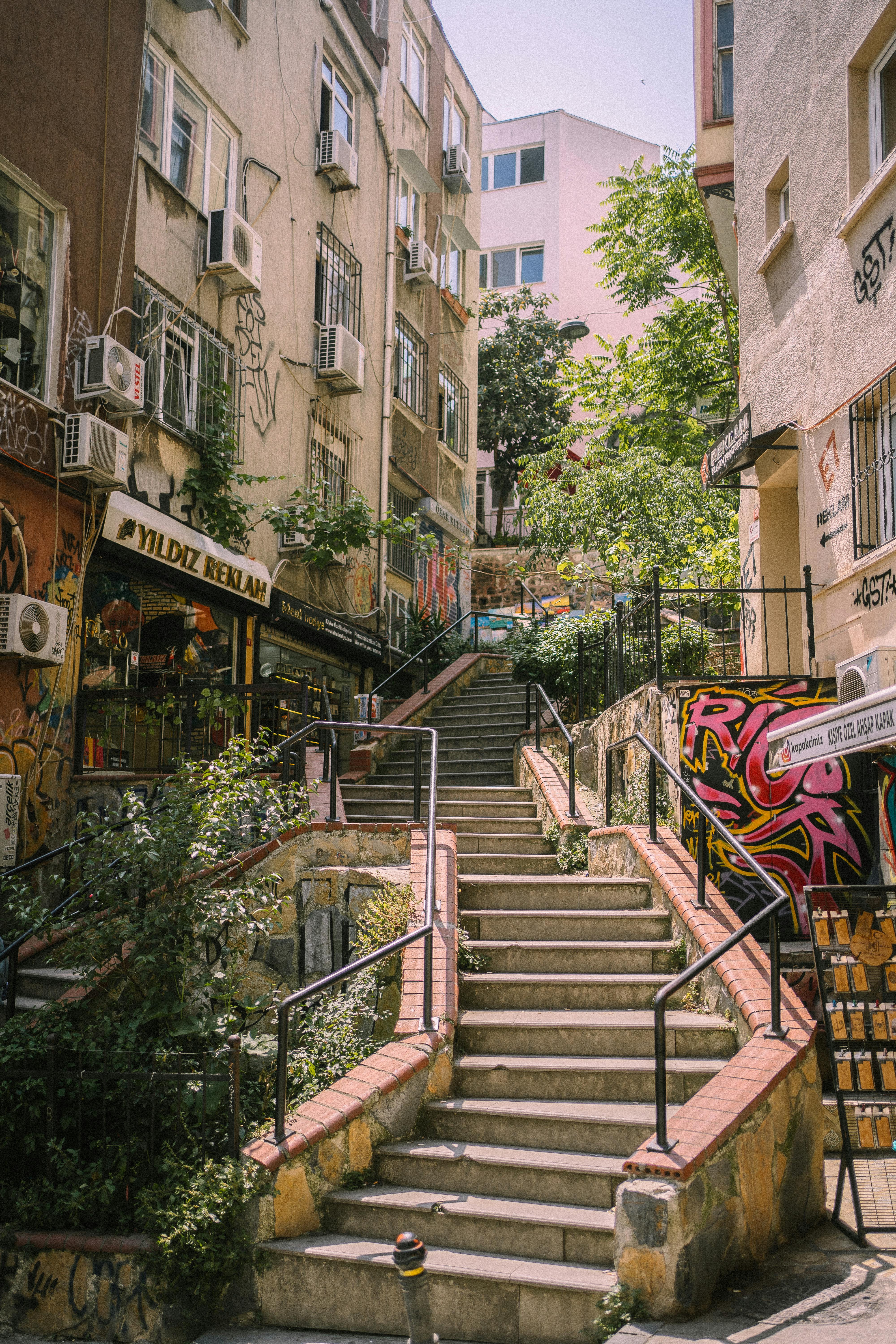 Explore a vibrant Istanbul alleyway featuring graffiti, steel railings, and lush greenery.