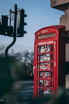 Classic red phone booth on a London street with a traffic light in the background.