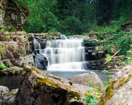 Free Serene waterfall surrounded by lush greenery and rocks in Lillehammer, Norway. Stock Photo