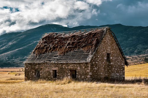 An Abandoned House on Grass Field Near the Mountain