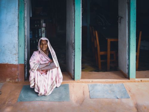 Free An elderly woman in traditional attire sitting peacefully in a doorway, capturing a moment of tranquility. Stock Photo