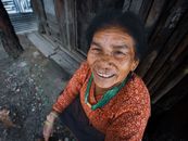 Elderly woman in traditional dress smiling warmly, showcasing cultural beauty and joy.