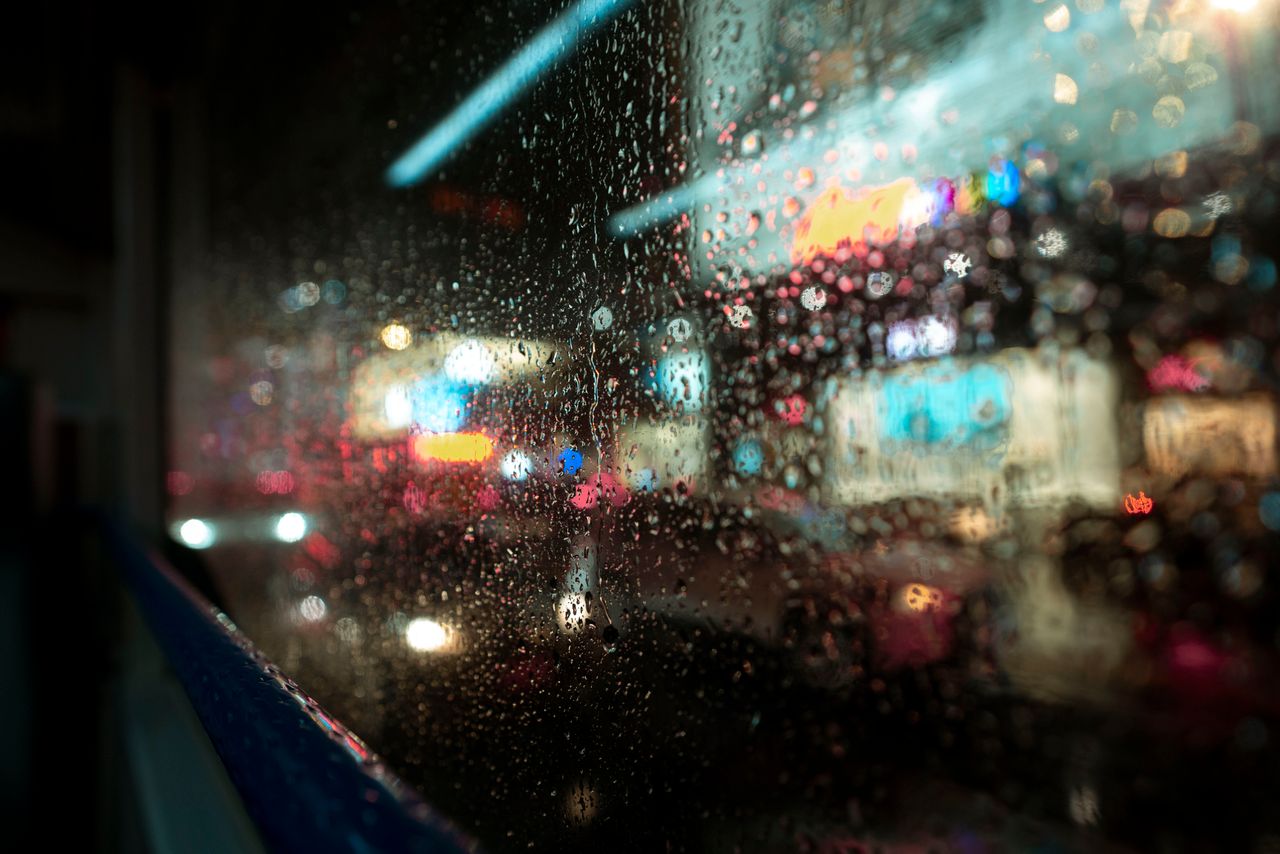 close up of raindrops on a window with blurred vibrant city lights