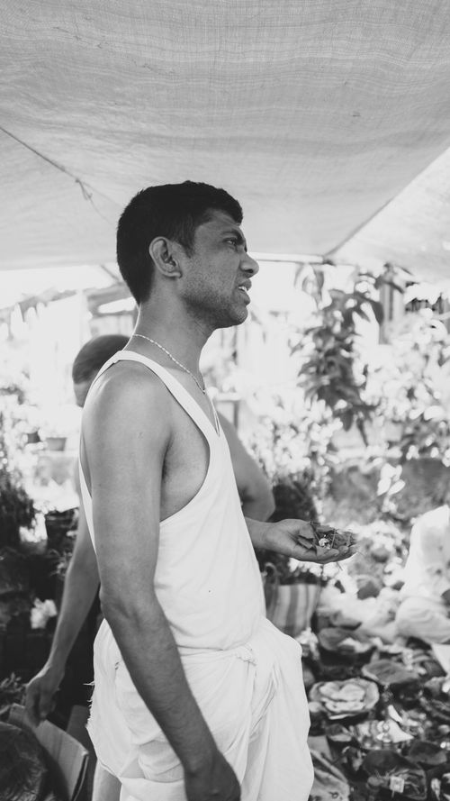 Free Black and white portrait of a man at a market, wearing a traditional outfit. Stock Photo