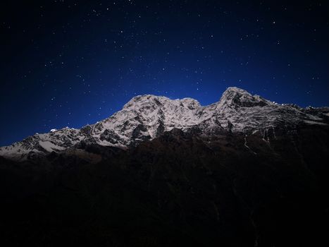 Stunning view of the Annapurna mountain range under a starry night sky in Nepal.