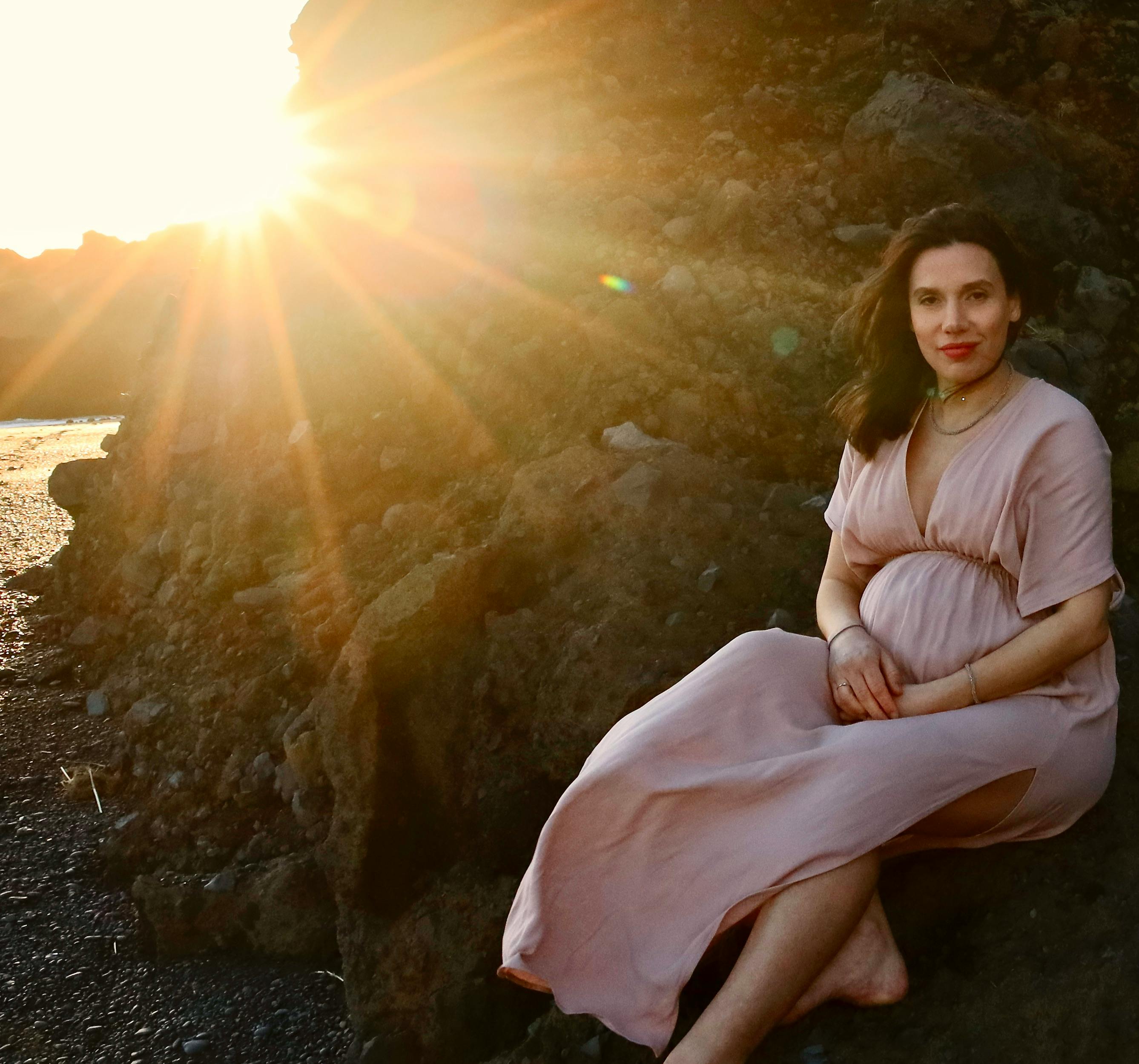 A serene portrait of a woman sitting on rocks during a sunset in Vík í Mýrdal, Iceland. - Vik