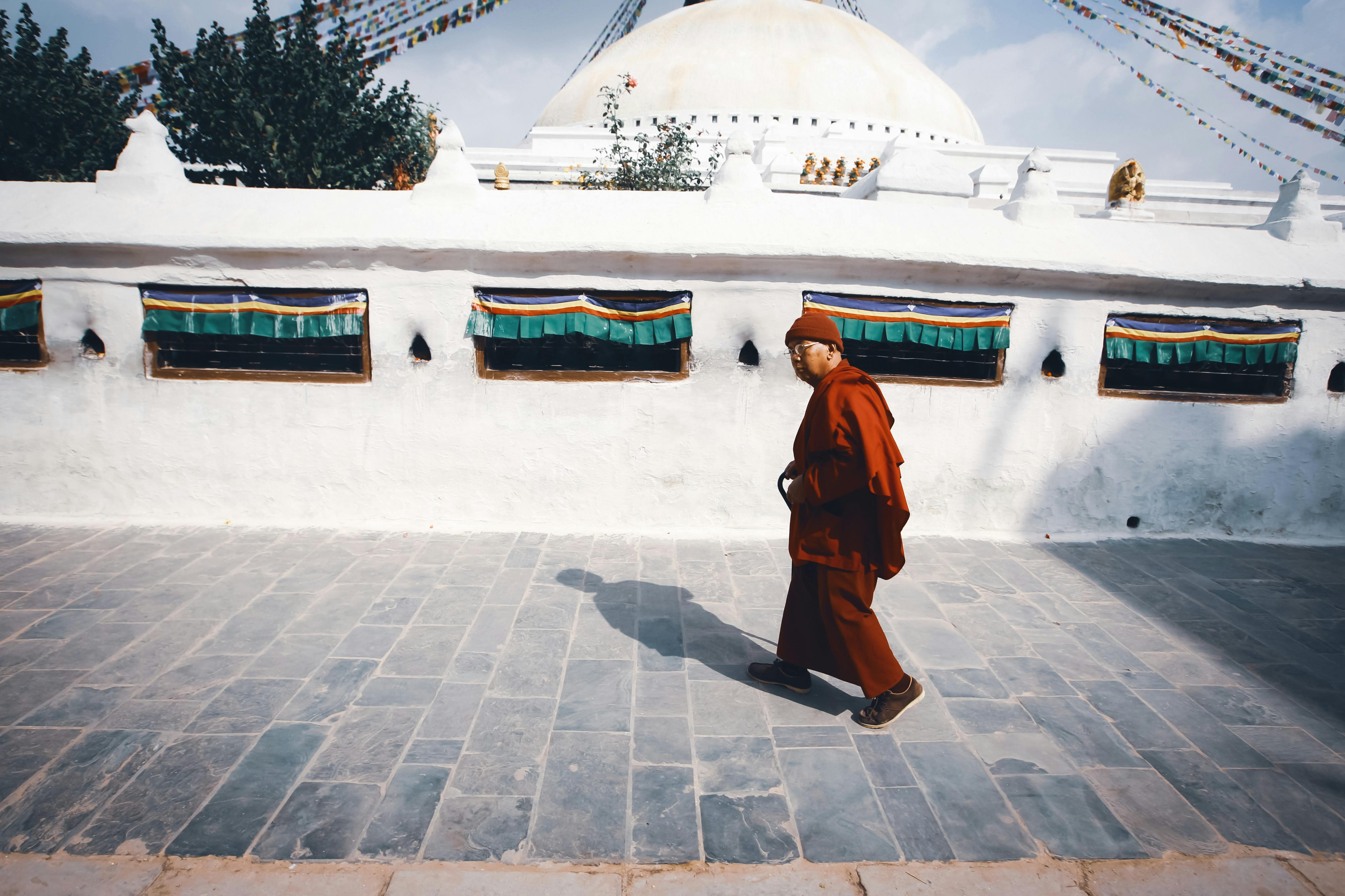 Photo of a Monk Walking on a Concrete Pavement · Free Stock Photo