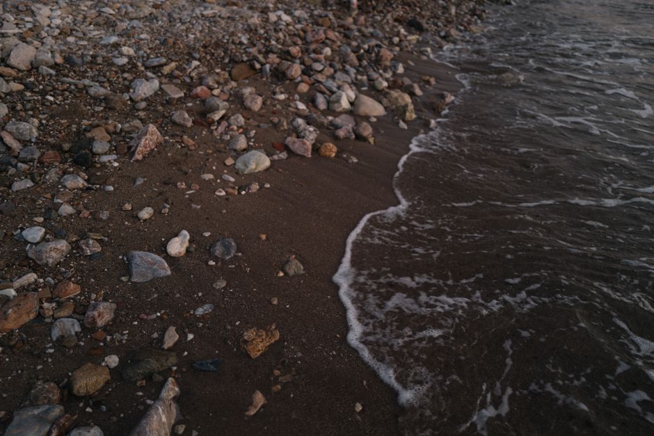 A serene view of a rocky shoreline with gentle waves lapping at the coast.
