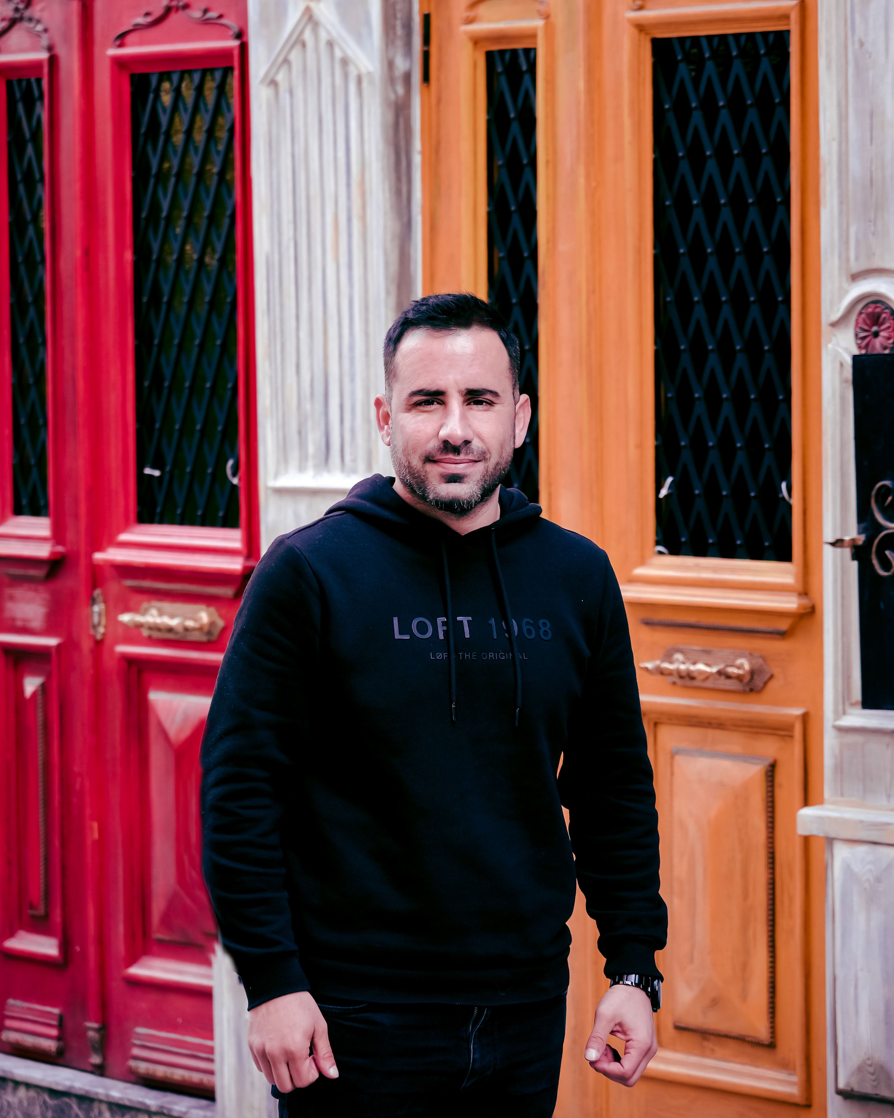 A happy man stands in front of vibrant doors in İstanbul, Türkiye.