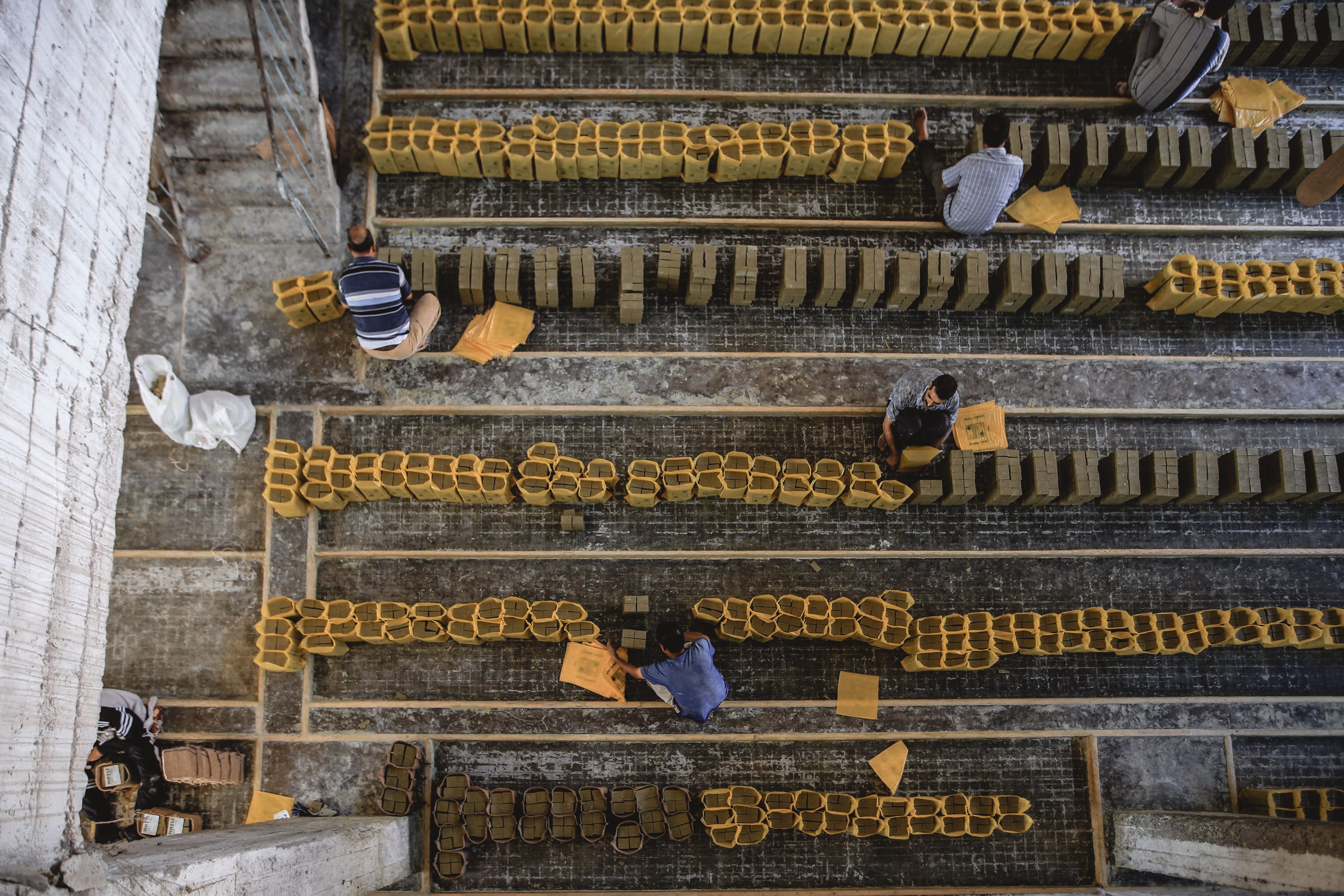 Top view of workers aligning clay bricks in a construction setting.