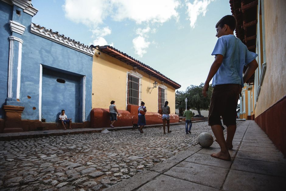 Kids enjoy a game of soccer on a colorful cobblestone street in a charming town.
