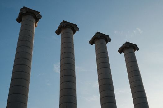 A low angle shot of Barcelona's iconic four columns under a clear blue sky, symbolizing Catalonian heritage.