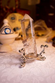 Close-up of a crystal quartz on a decorative holder with spiritual symbols nearby.