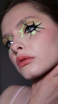 Close-up portrait of a woman with creative artistic makeup in a studio setting.