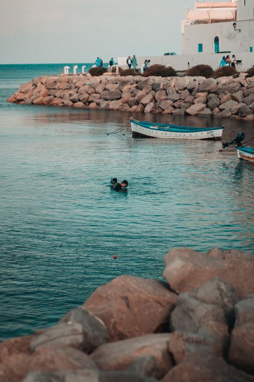 Free A picturesque view of divers and boats at Mahdia waterfront, Tunisia. Ideal for travel themes. Stock Photo