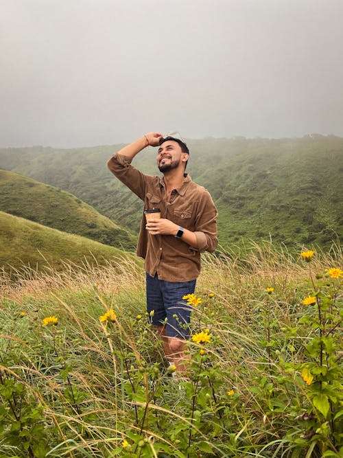 Man Standing on a Meadow in Mountains and Smiling 