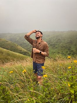 A man smiles with coffee in the green hills of El Crucero, Nicaragua.