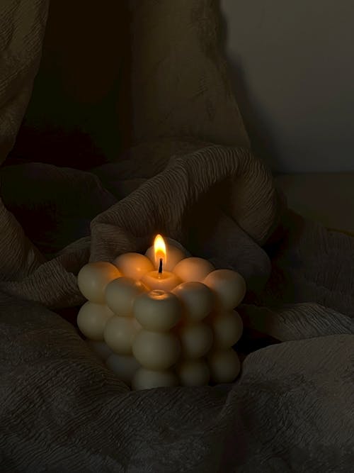Close-up of a Burning Candle in a Shape of a Cube with Bubbles