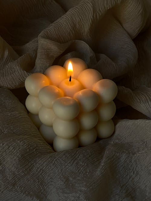 Lighted Candle on Top of a Beige Fabric