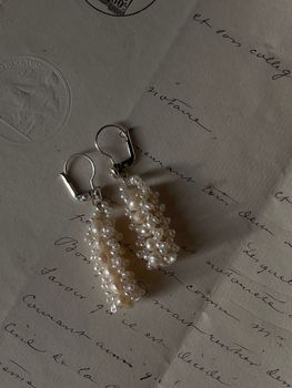 Close-up of pearl earrings on a vintage handwritten letter, highlighting elegance and fashion.