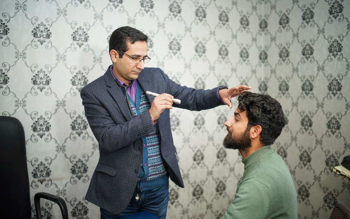 A doctor performs an eye examination on a patient in a clinical setting.