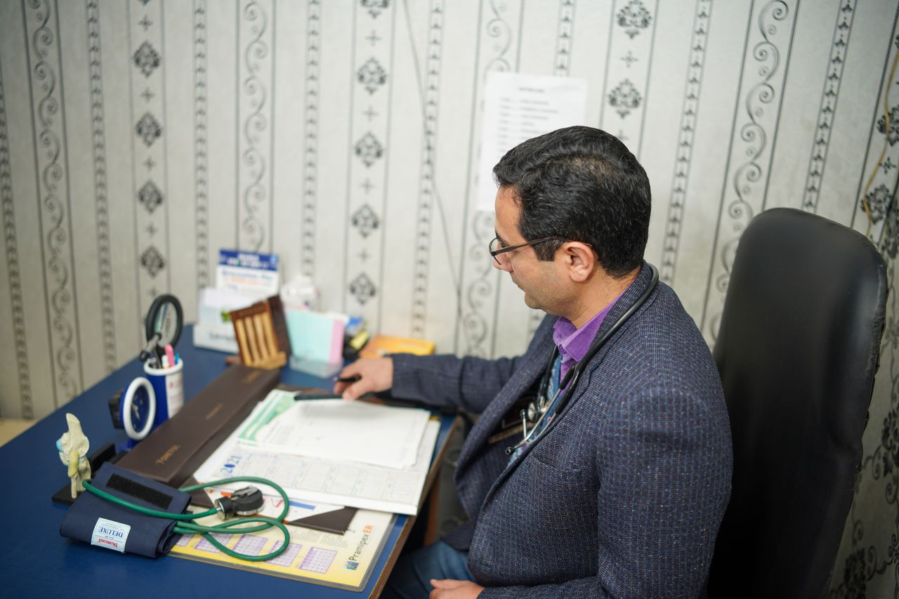 doctor reviewing medical documents at desk in clinic office