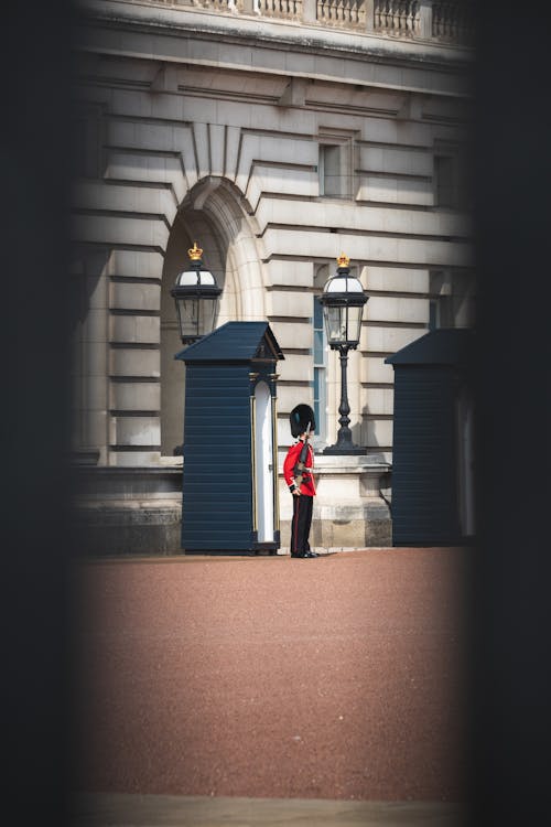 Person in Red Jacket and Black Pants Standing on Brown Brick Floor